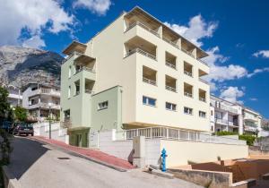 a white apartment building with a mountain in the background at Guesthouse Aroma in Makarska