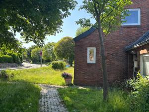 a brick house with a tree next to a sidewalk at Pension Perla Sylt in Sylt