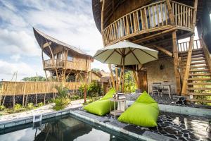 a house with a swimming pool and an umbrella at Uma D Mapad Sidemen in Sidemen