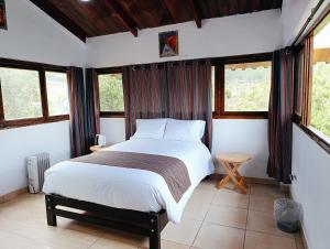 ein Schlafzimmer mit einem Bett in einem Zimmer mit Fenstern in der Unterkunft Samana House Valle Sagrado in Urubamba