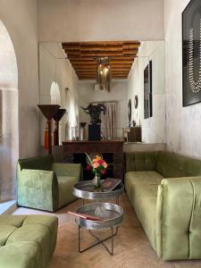 a living room with green couches and a table at Riad Bab Yacout in Marrakech
