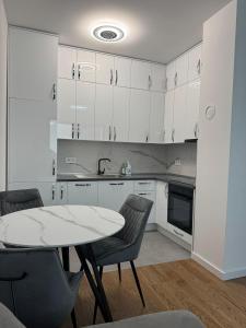 a kitchen with white cabinets and a table and chairs at Divna-Besplatan parking in Banja Luka