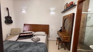 une chambre avec un lit, un miroir et une guitare dans l'établissement Sítio Topo do Mundo - Pólo Turístico INHOTIM na Serra da Moeda, à Brumadinho 90 autres photos