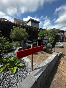 a red bench in a garden with two chairs at Oasen in Viborg