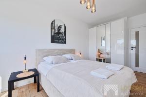 a white bedroom with a large bed and a table at Primo Deluxe by LookAp in Łódź