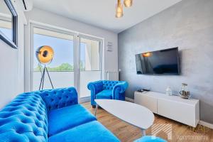 a living room with a blue couch and a tv at Primo Deluxe by LookAp in Łódź
