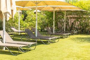 a group of lounge chairs and umbrellas on the grass at Camping Alannia El Pinar in Blanes