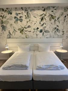 two beds in a bedroom with a floral wallpaper at Ferienhof Pankalla in Neubruchhausen