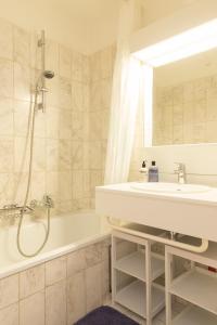 une salle de bain avec un lavabo, une baignoire et une douche dans l'établissement Atlantic 11A, à Ostende