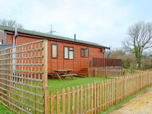 a wooden house with a fence and a picnic table at Rosewater Lodge in Saint Teath +2 photos