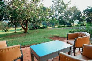 un patio con una mesa y sillas y un parque en Palm Valley Golf Resort, en Buzzi