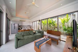 a living room with a green couch and a kitchen at Bang tao modern holiday style pool view high speed WiFi in Laguna Phuket