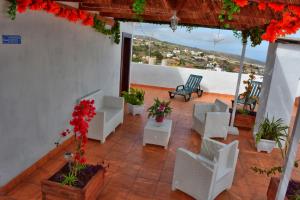 a patio with white chairs and red flowers on a building at Casa Yoel in Granadilla de Abona