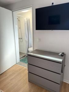 a bathroom with a dresser with a tv on the wall at Modern Cozy Studio Apartment & Terrace in Oldenburg +30 photos