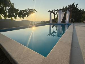 a swimming pool with the sun setting in the background at Villa Farah in Semizovac