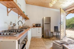a kitchen with a stove and a refrigerator at Rustic cabin with pond and deck in Aljezur