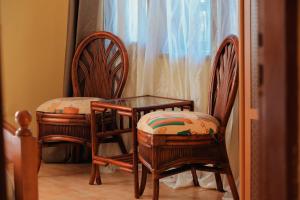 two wooden chairs and a glass table and two chairs at Palm Valley Golf Resort in Buzzi
