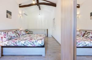 two beds in a room with white walls and wood floors at GuestHost - My Little Pink House in Selargius
