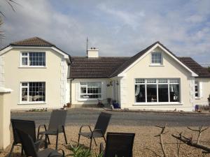 a white house with chairs in front of it at Lake View Apartment in Belmullet