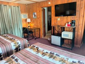 a hotel room with two beds and a flat screen tv at Big Sky Motel in Choteau
