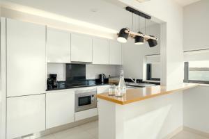 a white kitchen with white cabinets and a counter at Agua Hotels Riverside in Ferragudo