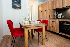 eine Küche mit einem Holztisch und roten Stühlen in der Unterkunft Appartement La Marmotte à Monetier grande terrasse in Le Monêtier-les-Bains + 13 Fotos