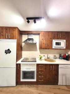 a kitchen with wooden cabinets and a white refrigerator at El Casillo de Gredos in Navacepeda de Tormes
