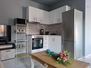 a kitchen with white cabinets and a wooden table with flowers at MariGold Villa in Prinos