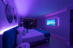 Playa Poesia By Casanita - Oceanfront Lux Studio في ميرتل بيتش: غرفة نوم أرجوانية مع سرير وتلفزيون +24 صورة