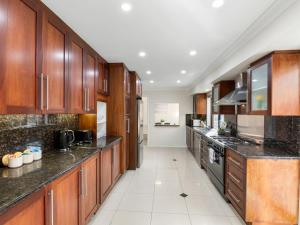 eine große Küche mit Holzschränken und schwarzen Arbeitsplatten in der Unterkunft Sunnybank Hills Retreat 6 Beds Near Market Square in Brisbane + 14 Fotos