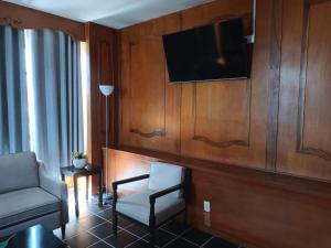 a living room with a chair and a tv at Hotel Rio Nazas in Torreón