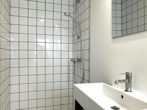 a white tiled bathroom with a sink and a shower at Spacious Apartment for 5 in Odense +9 photos