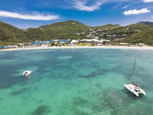 two boats sitting in the water near a beach at Koala1 Elegant 1BR Duplex, Anse Marcel, Sea View in Anse Marcel 