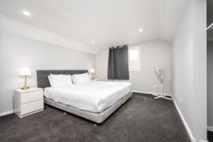 una camera da letto bianca con un letto grande e una finestra di Luxurious house near flemington racecourse a Melbourne