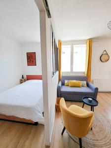 een slaapkamer met een bed, een bank en een stoel bij Les Amoureux in Royan
