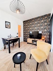 een woonkamer met een tafel en een televisie bij Les Amoureux in Royan