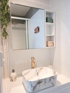 een badkamer met een marmeren wastafel en een spiegel bij Les Amoureux in Royan
