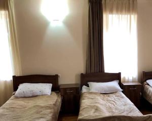 a bedroom with two beds and a light on the wall at guest house dede in Itʼkhvisi