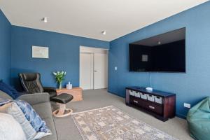 un soggiorno con parete blu e TV a schermo piatto di The Middleton Room a Queenstown