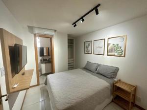 a bedroom with a bed and a flat screen tv at Canto da Jandaia Imbassaí in Imbassai