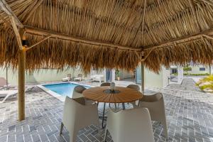 a patio with a table and chairs and a pool at Villa Mambo Beach with Private Pool in Willemstad
