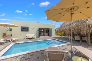 a villa with a swimming pool and an umbrella at Villa Mambo Beach with Private Pool in Willemstad