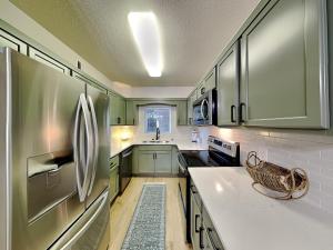 a kitchen with green cabinets and a stainless steel refrigerator at Mountain Breeze Retreat at Whispering Pines 512 in Pigeon Forge