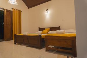 twee bedden in een slaapkamer met gele lakens en gele kussens bij Lakeshore Resort in Anuradhapura