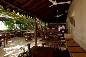 a restaurant with tables and chairs and a chef in the background at LAMU HOUSE in Lamu