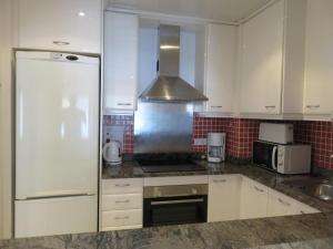 a kitchen with white cabinets and a stainless steel refrigerator at Apartamentos Las Brisas 3-2 in Torroella de Montgrí