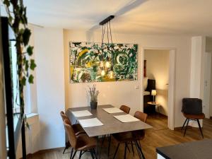 a dining room table with chairs and a painting on the wall at Der Platzhirsch - Design-Apartment in grüner Oase in Freiburg im Breisgau