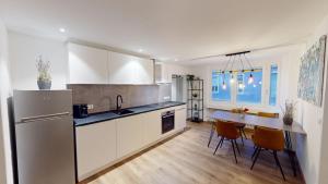 a kitchen with a refrigerator and a table with chairs at Der Platzhirsch - Design-Apartment in grüner Oase in Freiburg im Breisgau