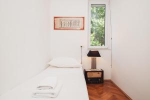 a white bedroom with a bed and a window at Spinut Urban Retreat in Split