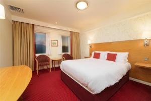 a hotel room with a large bed and a table at Best Western Plus Milford Hotel in South Milford